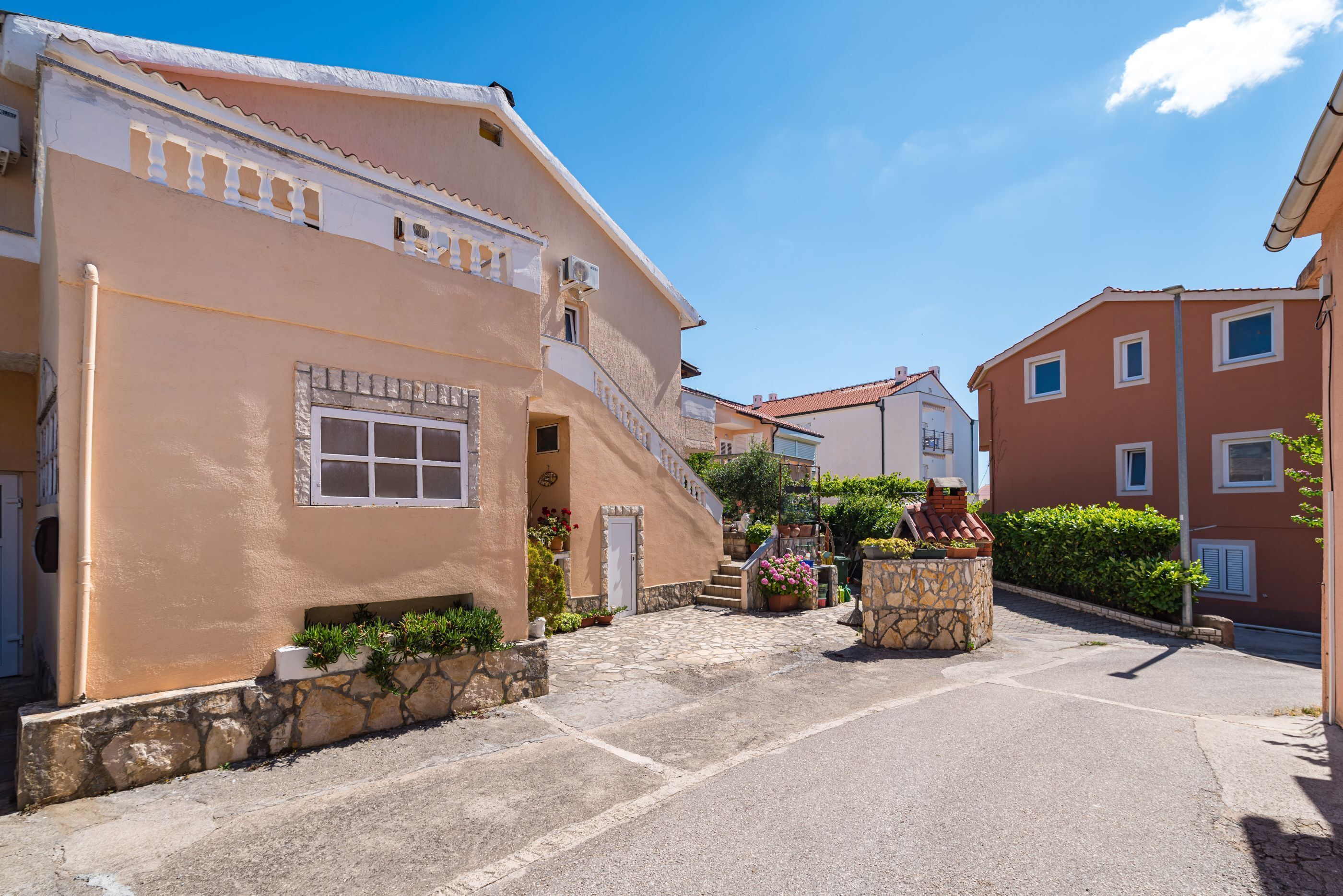 A building with a stone facade, a staircase, and a small garden area.