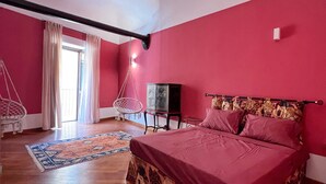 A bedroom with a large bed, a hanging chair, a TV, and a wardrobe. - THE ROOTS (VACATION HOME) (Palermo)