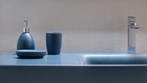 A bathroom sink with a blue faucet, a blue soap dispenser, and a blue cup. - THE ROOTS (VACATION HOME) (Palermo)