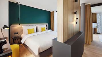 Quarto de hotel moderno com cama, mesa de cabeceira, abajur e vista da cidade através de amplas janelas.