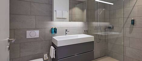 A modern bathroom with a toilet, sink, and shower.