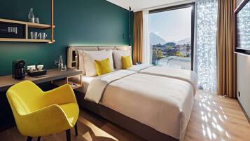 Ein Hotelzimmer mit Bett, Schreibtisch, Stuhl und Blick auf eine Stadtlandschaft.