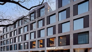 Ein modernes Gebäude mit mehreren Schaufenstern, darunter eines mit der Aufschrift 'Essential by Dorint'.