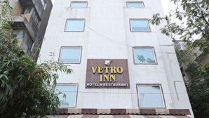 A hotel with a sign reading "Vetro Inn Hotel & Restaurant" and a modern architectural design.