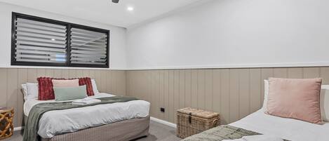 A bedroom with a bed, a ceiling fan, a window with blinds, and a small wicker basket.