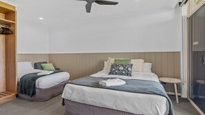 Ein Hotelzimmer mit zwei Betten, einem Deckenventilator, einem kleinen runden Tisch und einem Kleiderschrank.