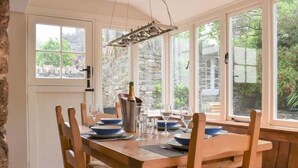 A wooden dining table set with plates, glasses, and a bottle of champagne. - The Glen, Ugborough, South Devon (Ugborough)