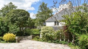 A stone pathway leading to a house surrounded by lush greenery and trees. - The Glen, Ugborough, South Devon (Ugborough)
