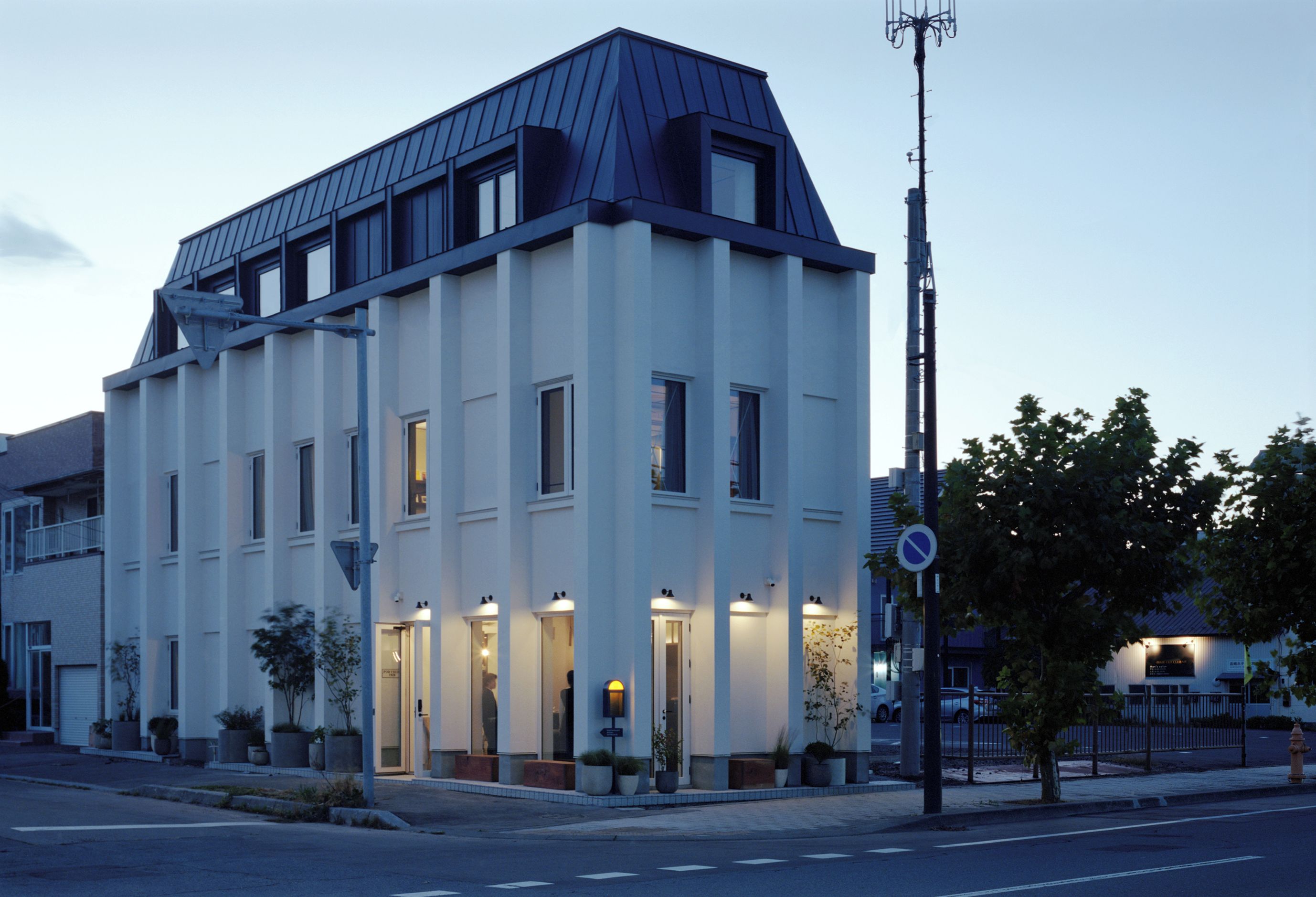 A modern building with a flat roof, multiple windows, and a well-lit entrance.