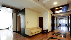 A modern lobby with a sofa, a small table, and a patterned floor. - Fressotel Seetharam (Coimbatore)