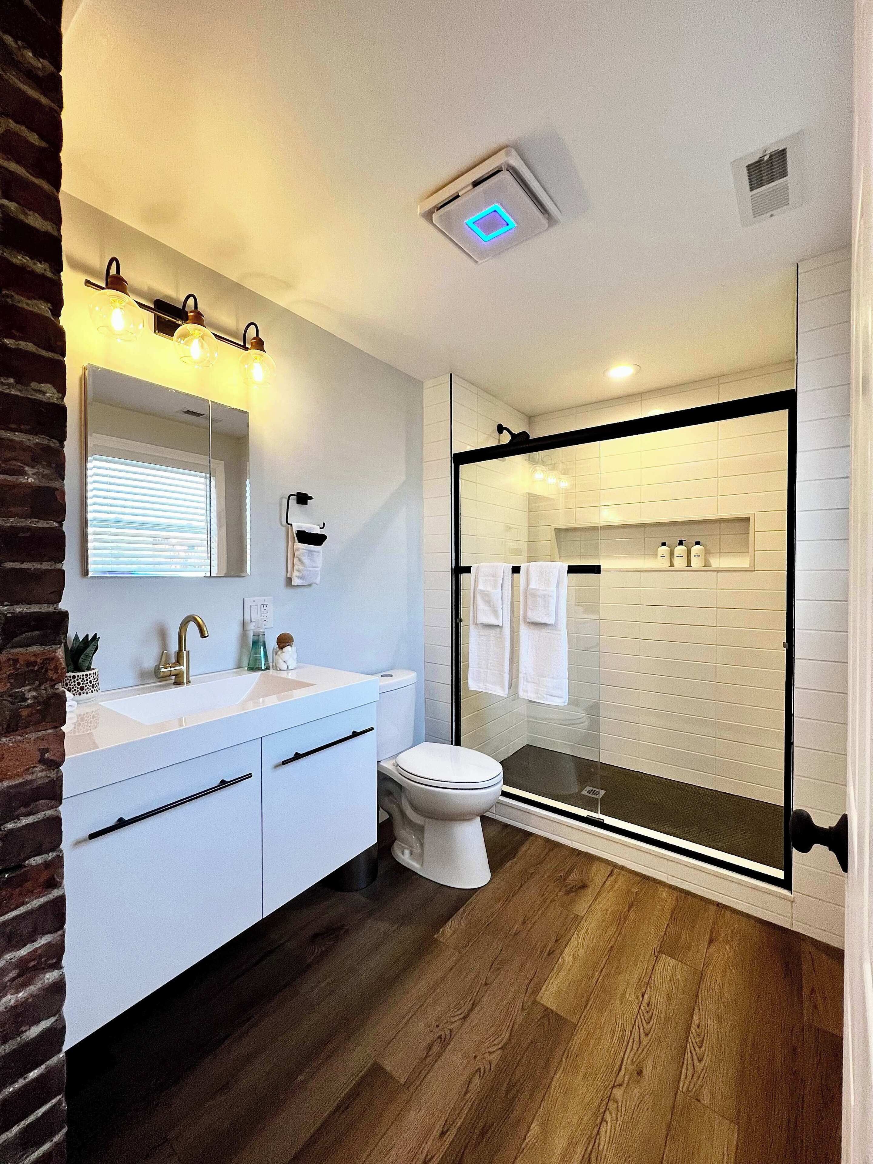 A modern bathroom with a glass shower enclosure, a white sink, and a toilet.