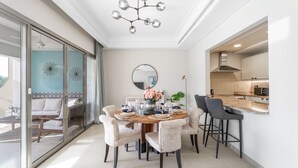 Un espace repas moderne avec une table ronde, des chaises en osier et un lustre.