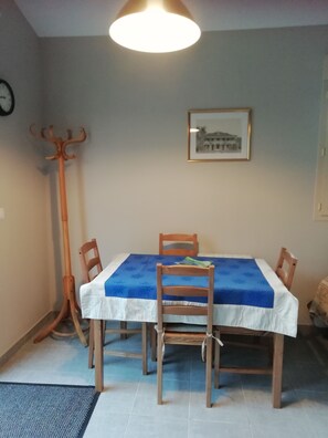Un comedor con una mesa dispuesta para cuatro personas, un perchero y un cuadro en la pared.