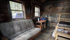 Een gezellig interieur van een chalet met een bank, een eettafeltje en een houten vloer.