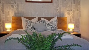 Una cama bien hecha con almohadillas de diseño floral, un cabecero y dos lámparas de noche.