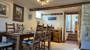 Ein Essbereich mit Holztisch und Stühlen, ein Küchenbereich mit Herd und eine Steinwand.