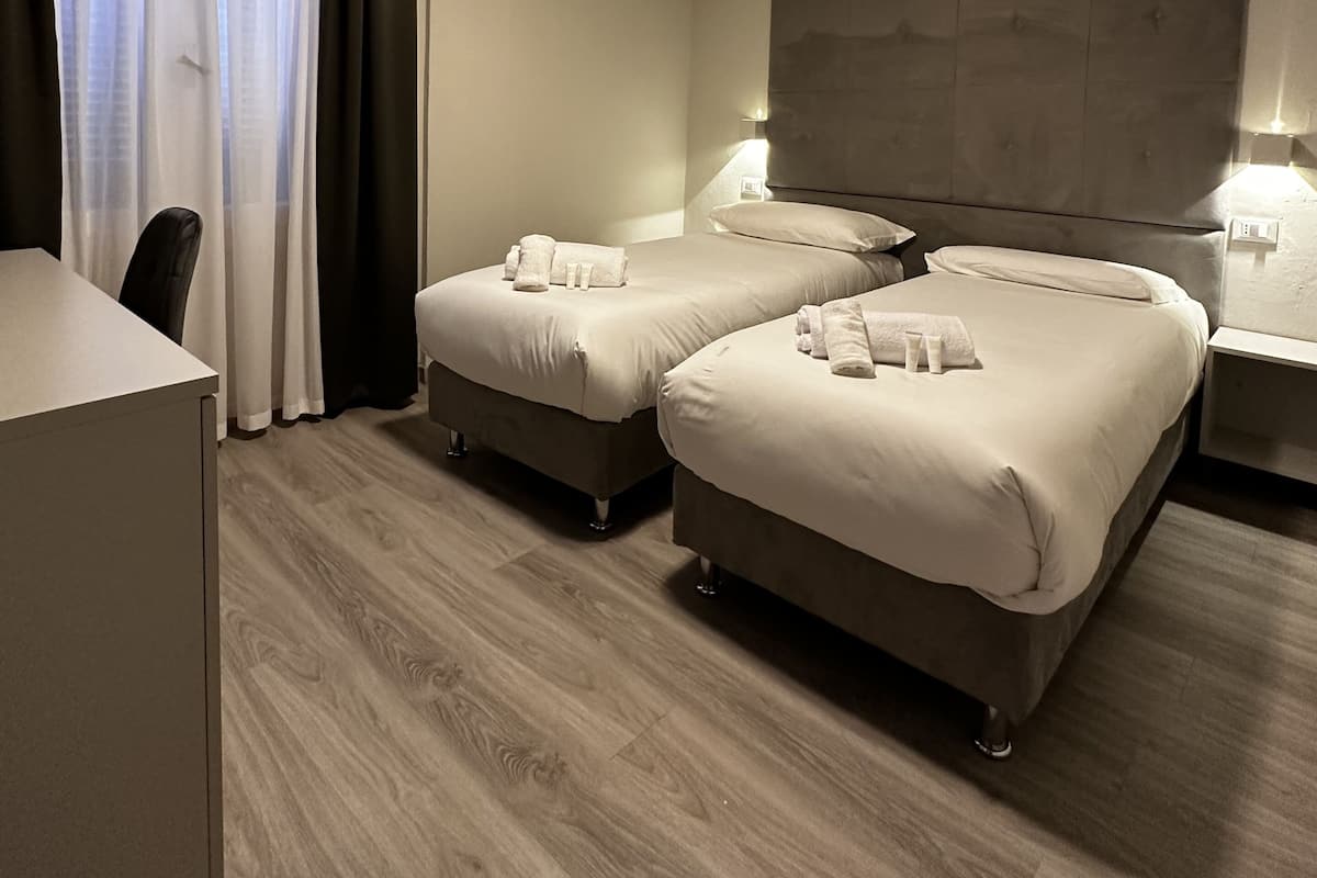 A hotel room with two beds, a desk, and a television.