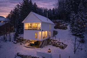 A two-story cabin with a balcony, surrounded by snow-covered trees. - On The Rocks, Spa, Babyfoot, vue magnifique (Saint-Côme)