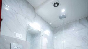 A modern bathroom with a toilet, sink, mirror, and shower. - The Crown Hotel (Agra)