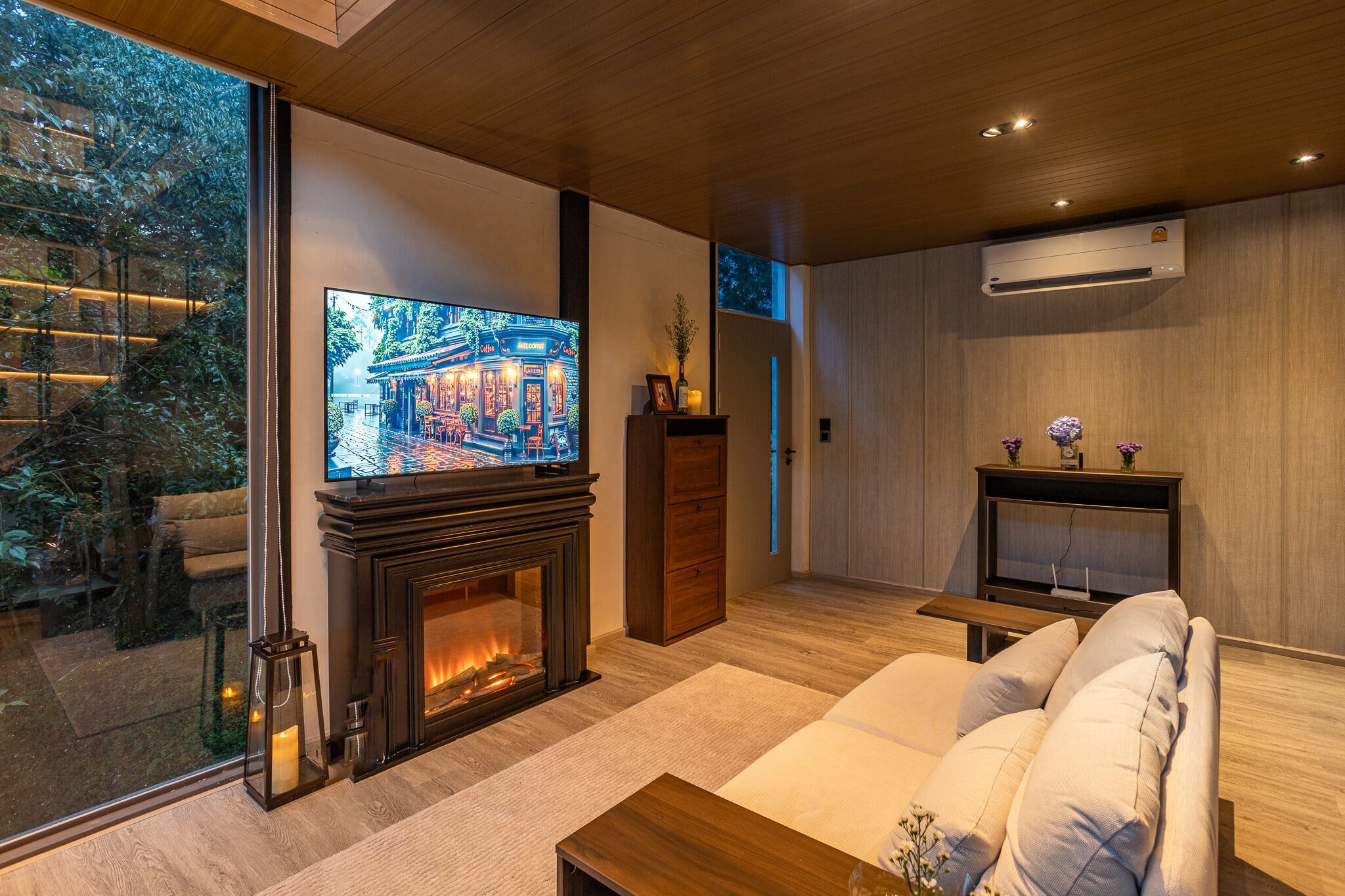 Una sala de estar moderna con chimenea, un televisor grande y un sofá.