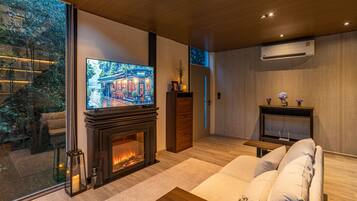 Una sala de estar moderna con chimenea, un televisor grande y un sofá.