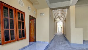 A corridor with tiled flooring, wooden-framed windows, and a door marked with the number 1.