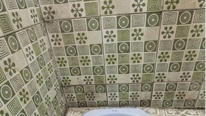 A bathroom with a toilet, tiled walls, and a patterned floor.