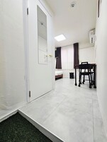 Habitación de hotel con cama, escritorio y silla. Se ve una ventana con cortinas y un aire acondicionado en la pared.