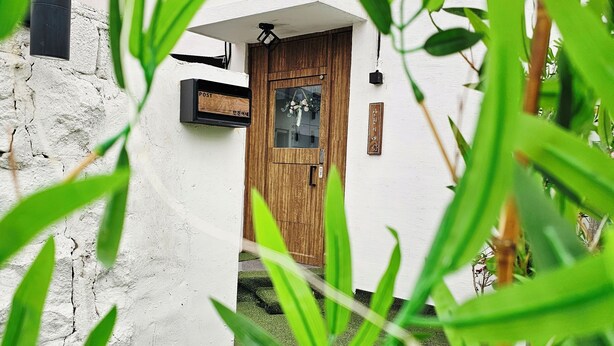A white building with a wooden door, a small window, and a signboard. - Anjin's Guest House (Mokpo)