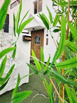 A white building with a wooden door, a small window, and a signboard. - Anjin's Guest House (Mokpo)