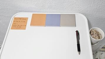 A white desk with a pen, a notepad, and sticky notes.