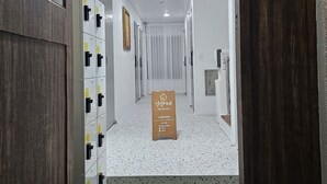 A hotel hallway with lockers, a signboard, and a unique ceiling light fixture. - Anjin's Guest House (Mokpo)
