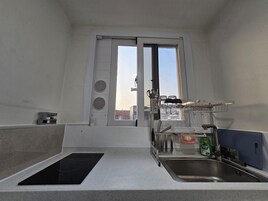 Una cocina compacta con ventana, estufa integrada, pileta y un escurreplatos.