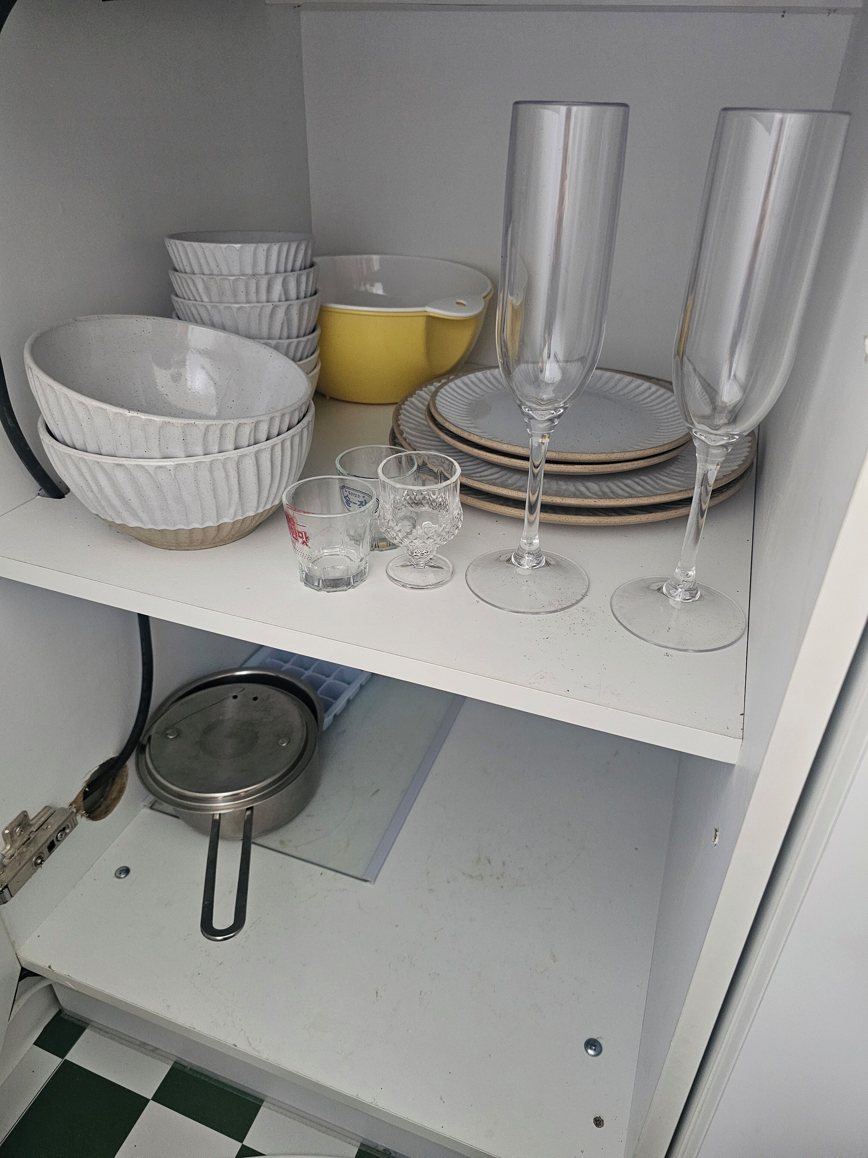 Una zona de cocina con armarios blancos, una estufa y varios platos y vasos en los estantes.