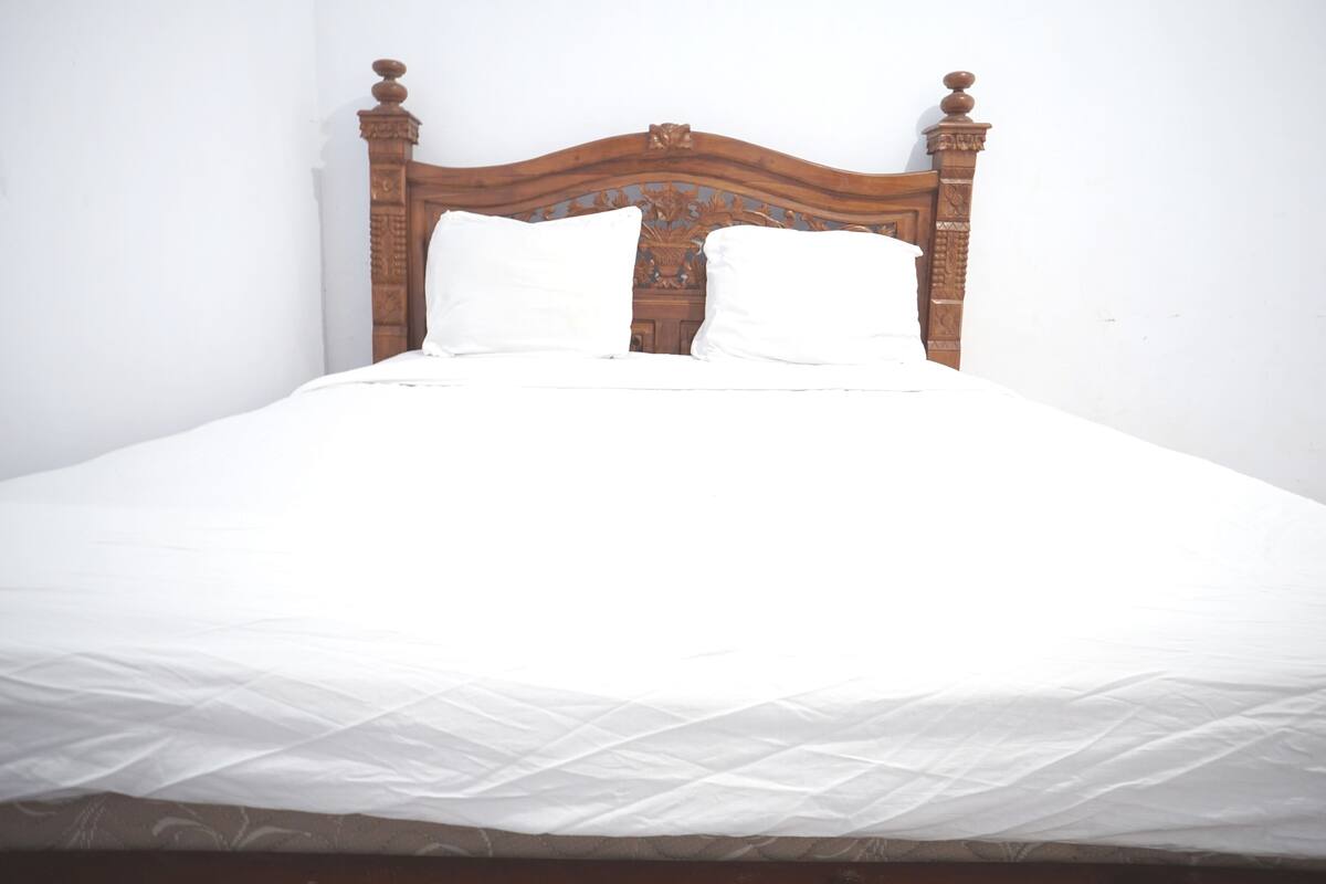 A bed with a wooden headboard and two white pillows.