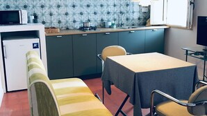 Une cuisine compacte équipée d’un four à micro-ondes, d’une cuisinière et d’un évier. On y trouve une table à manger avec des chaises, un banc et un téléviseur.
