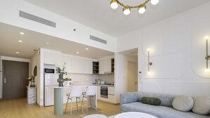 A modern kitchen with white cabinets, a central island with bar stools, and a dining area. - LUX The Downtown Zabeel View Suite 2 (Dubai)