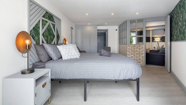 A modern bedroom with a large bed, a bedside table, and a wall-mounted lamp. - 1-bed Flat in West London, Sleeps 2 (London)