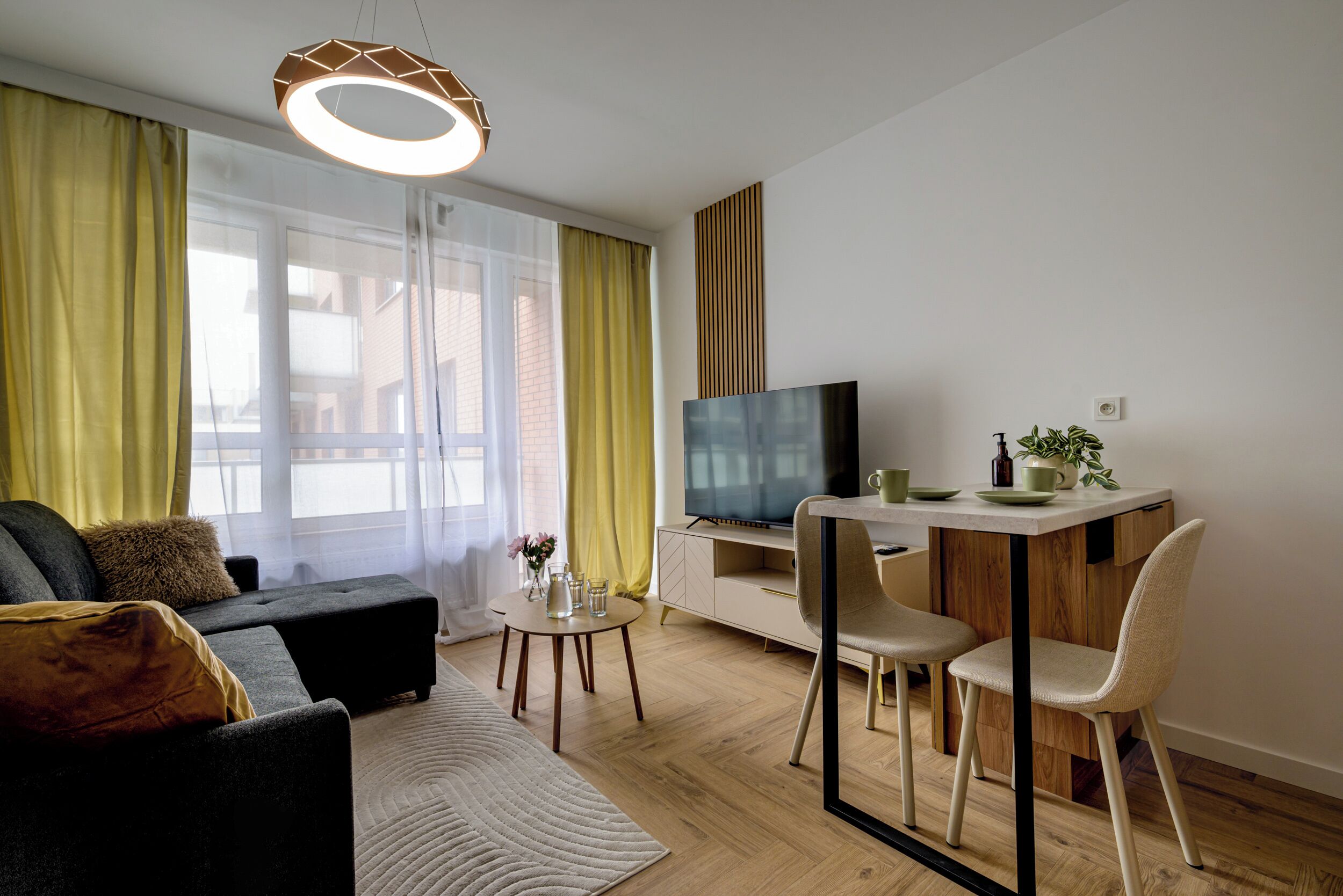 Un salon moderne comprenant un canapé, une table basse, un téléviseur et un coin repas avec des chaises et une petite table.