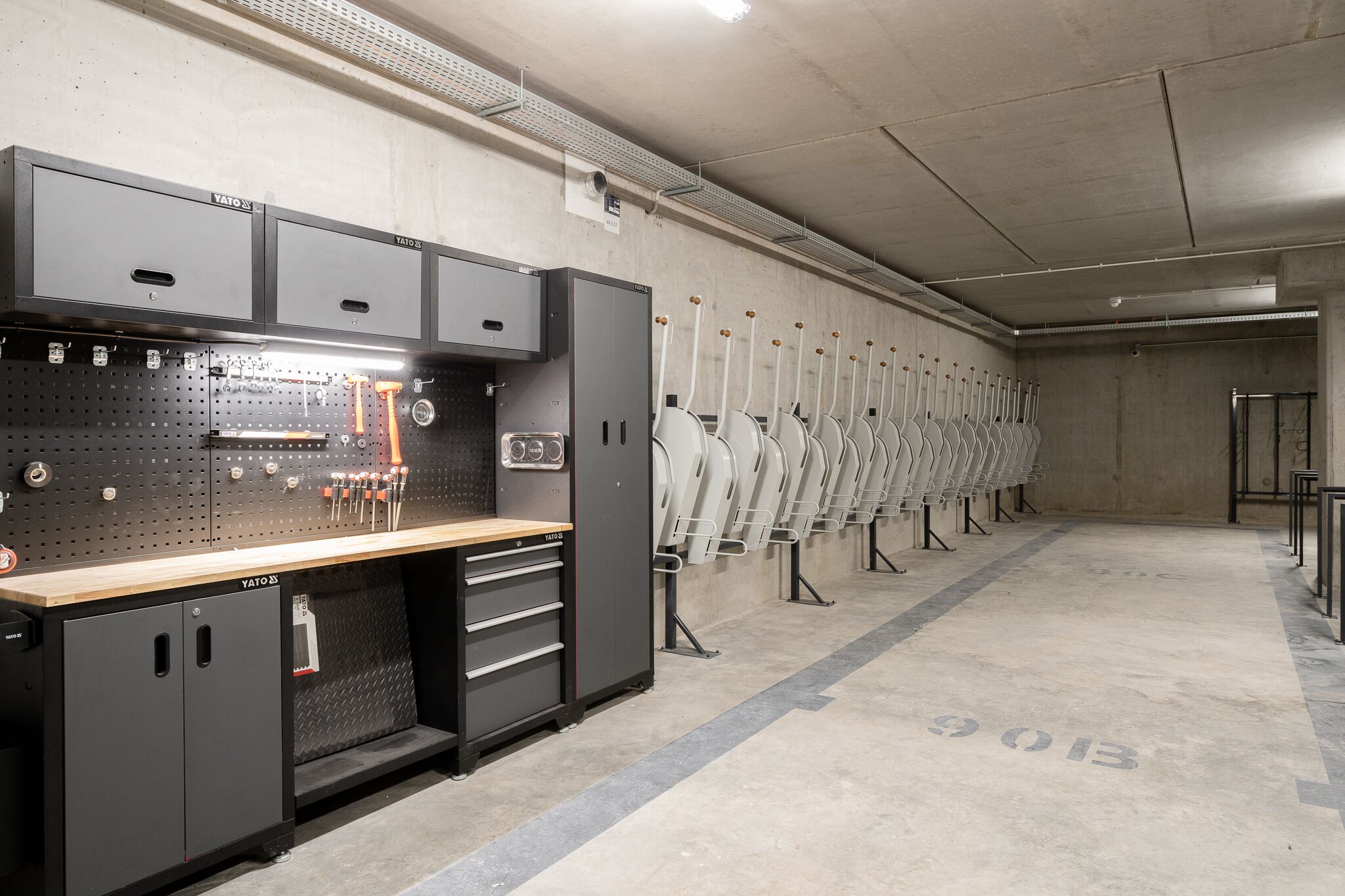 Un espace intérieur bien aménagé, avec un mur équipé de panneaux perforés, des armoires de rangement et des rangées de chaises.