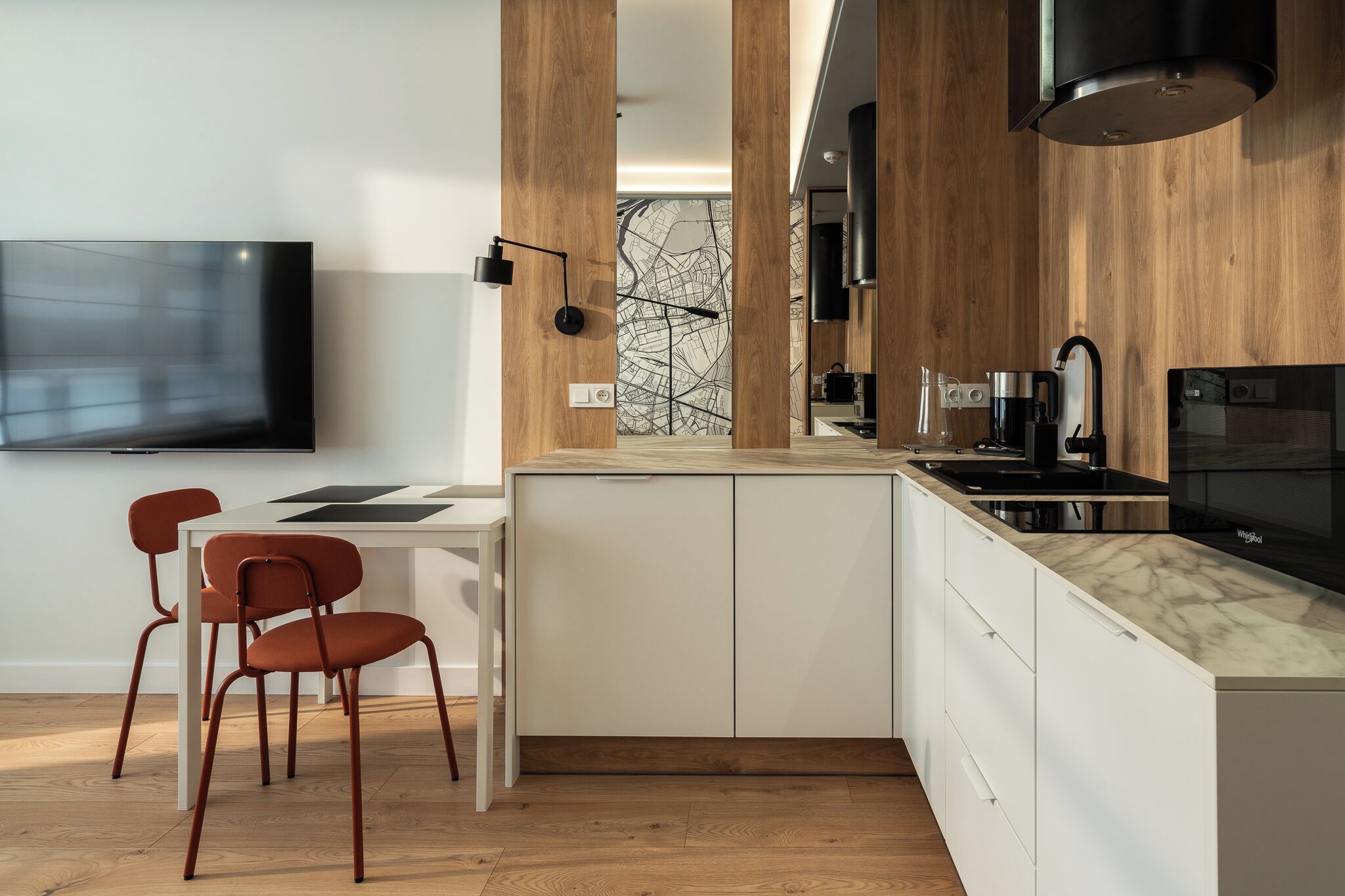 Une cuisine moderne avec un mur d’accent en bois, un îlot central intégré et un téléviseur à écran plat fixé au mur.