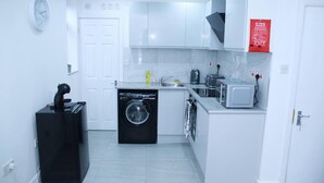 Une cuisine compacte équipée d’un lave-linge, d’un grille-pain et d’un évier.