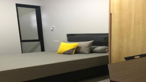A small, single-bed room with a wooden table and a mirror on the wall. - OYO Life 92770 Cozy Puri 22 (Jakarta)