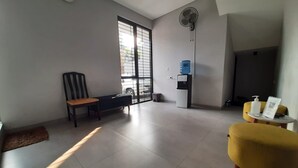 A modern living room with a sofa, a chair, a small table with a bottle, and a water dispenser. - OYO Life 92770 Cozy Puri 22 (Jakarta)