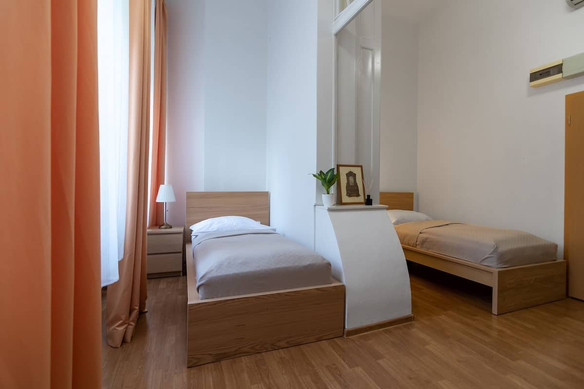 A modern bedroom with two single beds, a nightstand, a lamp, and a framed picture on the wall.