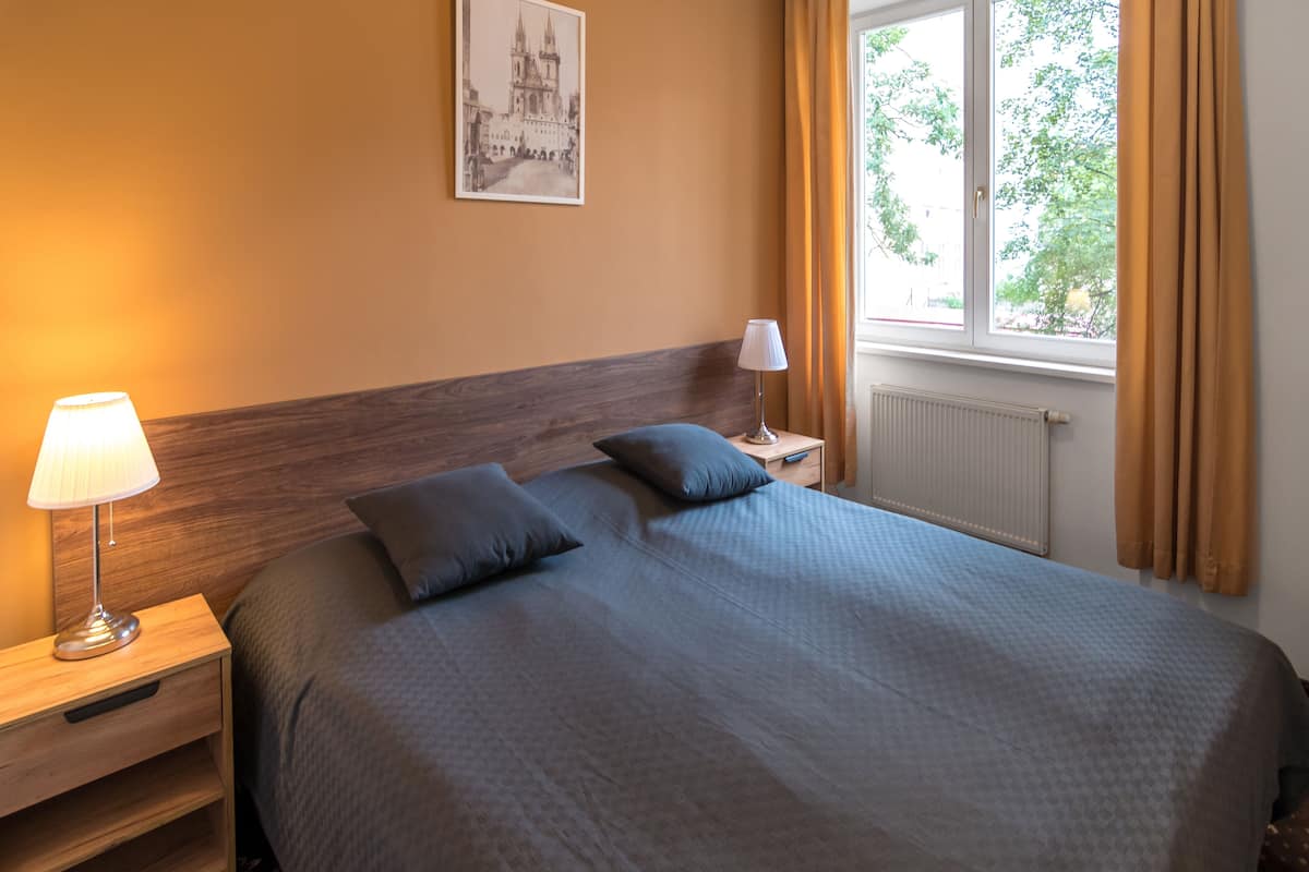 A neatly made bed with a headboard, a bedside lamp, and a framed picture on the wall.
