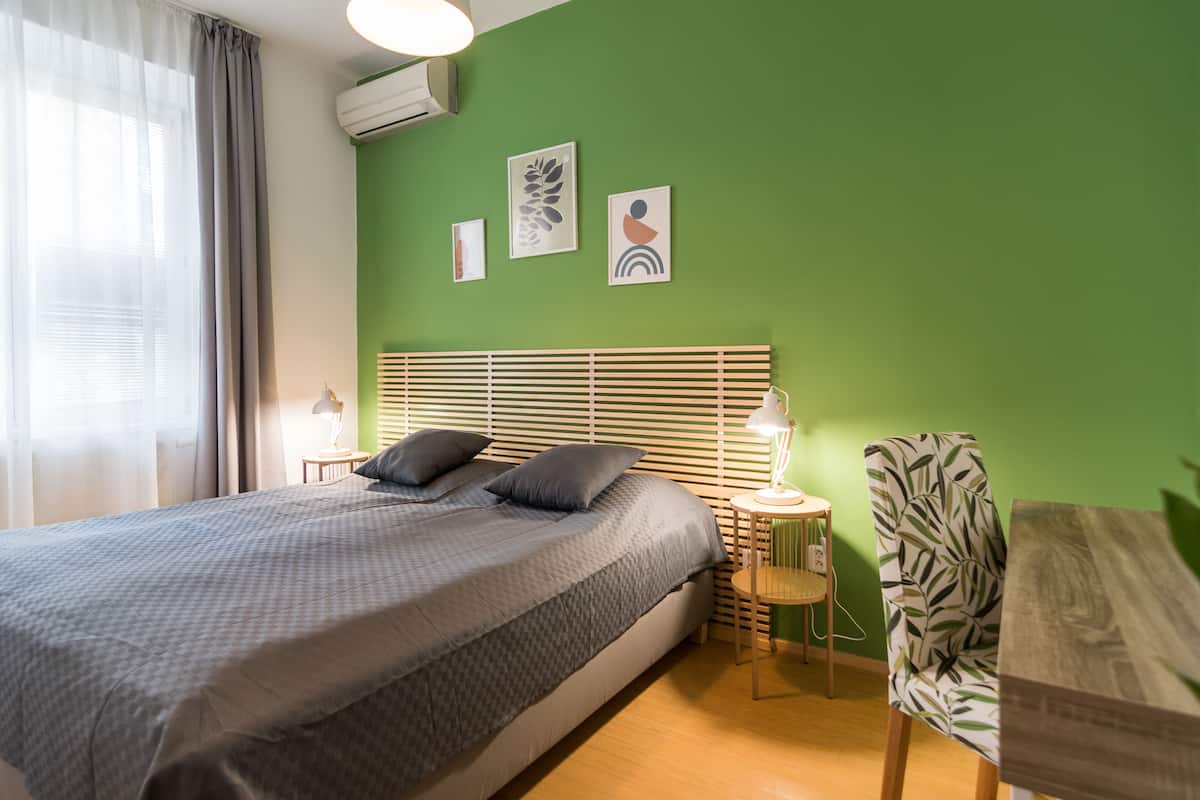 A neatly arranged bedroom with a bed, bedside tables, and a chair.