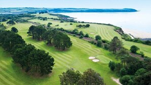 Eine Vogelperspektive auf einen Golfplatz mit Strand und einem Wasserkörper im Hintergrund.
