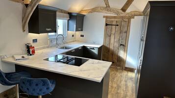 Une cuisine moderne avec un plan de travail en marbre, des meubles noirs et un plafond en bois.