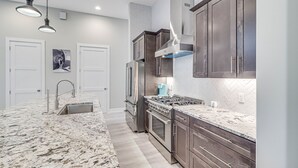 A modern kitchen with granite countertops, stainless steel appliances, and dark wooden cabinets.